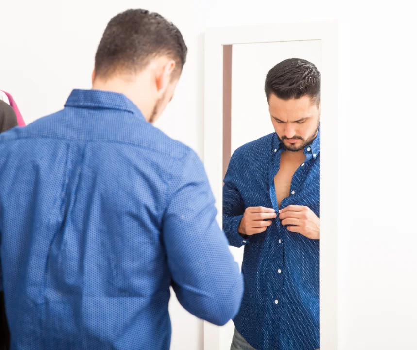 nipple puffy after gynecomastia surgery: man buttoning his shirt