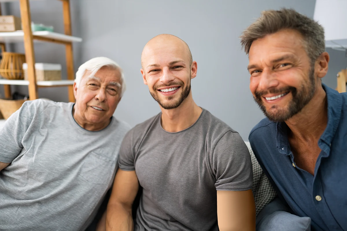 Best age for gynecomastia: Three men of different ages sitting together and smiling at the camera